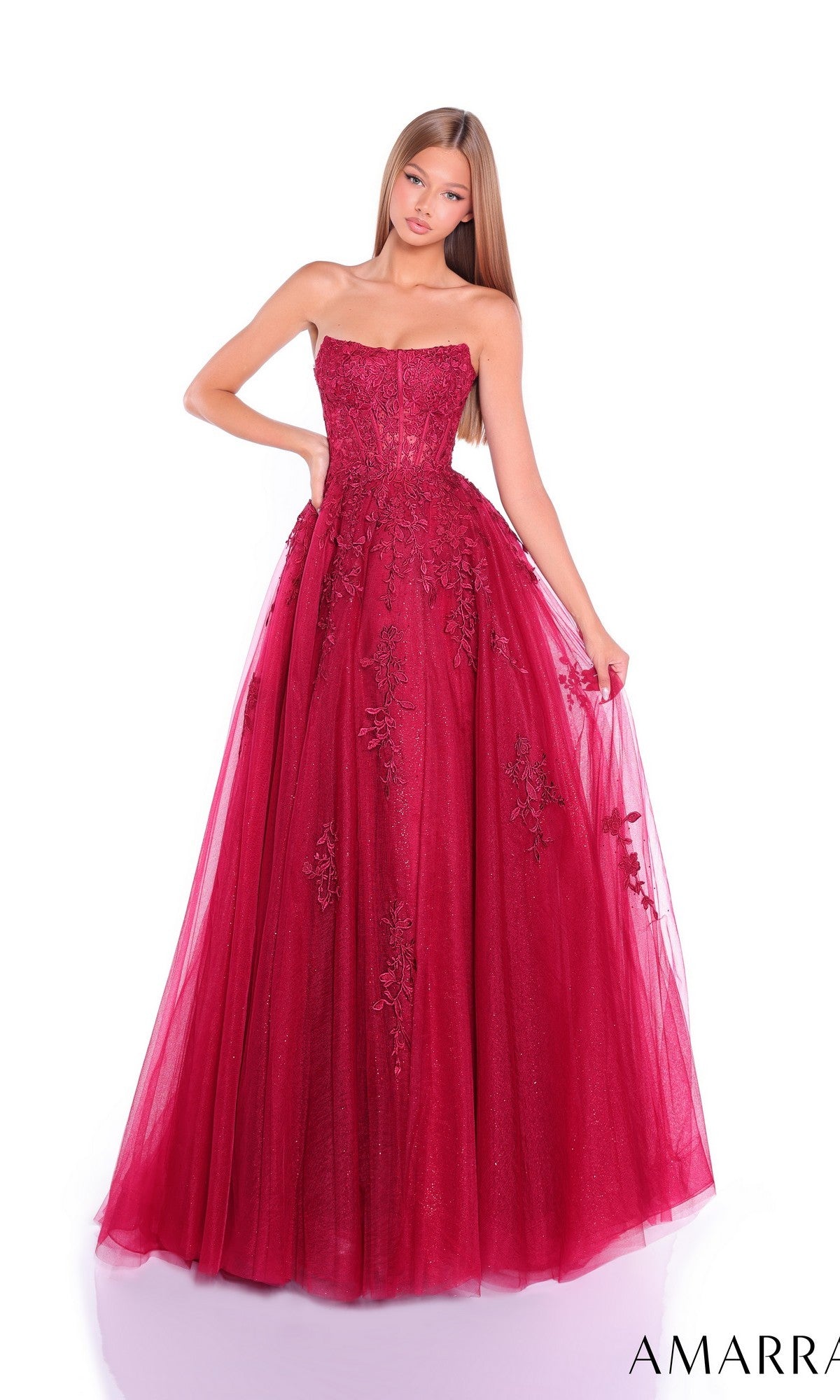 A young woman models the Amarra 88950 Strapless Embroidered Prom Ball Gown, featuring a sweetheart neckline and floral embroidery, standing against a white background to showcase the elegant A-line formal dress.